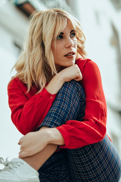 Fille blonde avec une chemise rouge, profitant de la vie en plein air.