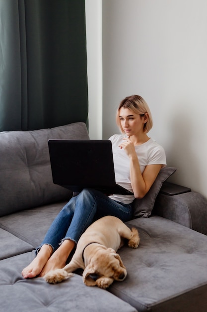 fille blonde avec un chien assis sur le canapé avec un espace pour ordinateur portable pour le texte