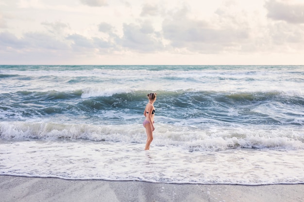 Fille blonde en cours d'exécution et de sauter sur la plage au bord de la mer bleue en vacances d'été à l'heure de la journée.