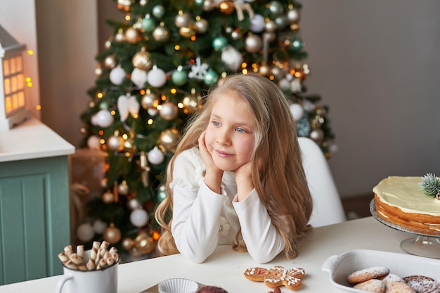 fille blonde dans la cuisine du nouvel an avec des petits gâteaux et des bonbons