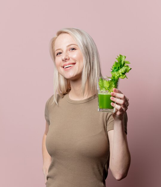 Fille blonde avec du jus de céleri rose