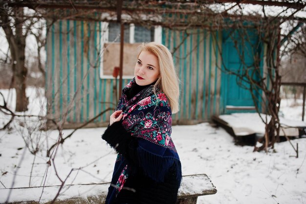 Fille blonde avec écharpe brodée à la main posée au jour d'hiver. Mouchoir de femme.