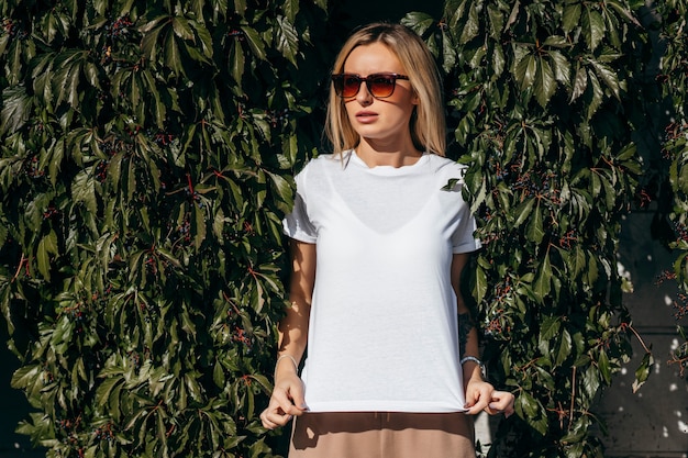 Fille blonde élégante portant des lunettes et t-shirt blanc