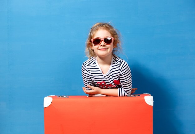 Fille blonde enfant avec valise vintage rose prêt pour les vacances d'été. Concept de voyage et d'aventure.