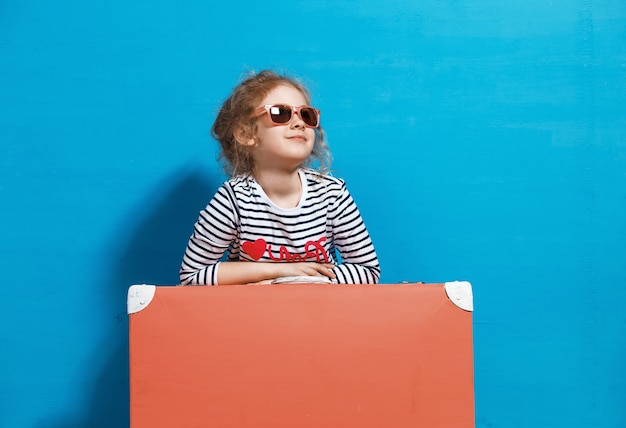 Fille blonde enfant avec valise vintage rose prêt pour les vacances d'été. Concept de voyage et d'aventure.