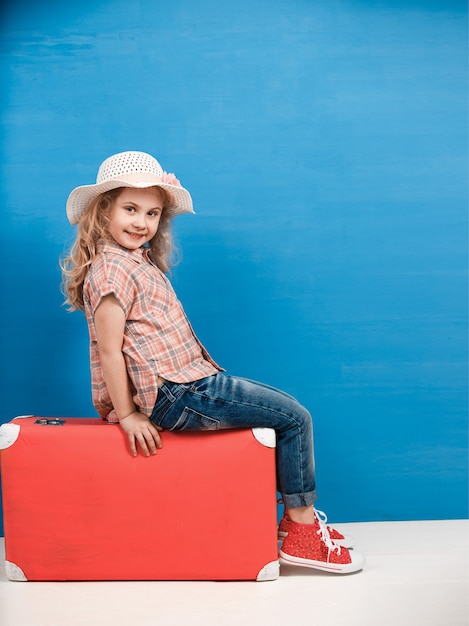 Fille blonde enfant avec valise vintage rose prêt pour les vacances d'été. Concept de voyage et d'aventure.