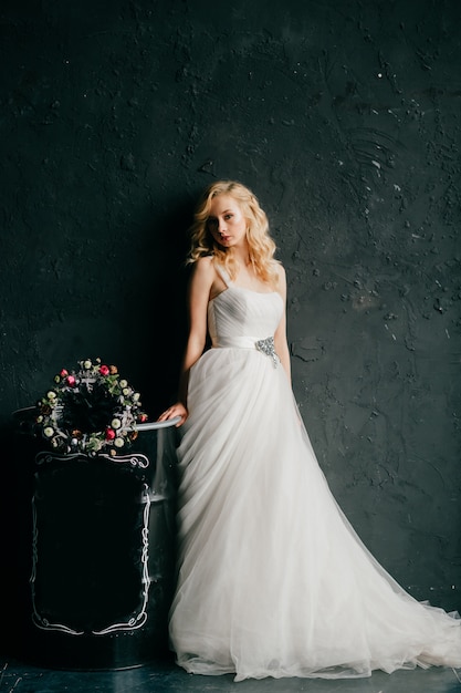 Fille blonde européenne en portrait de studio de robe de mariée blanche.