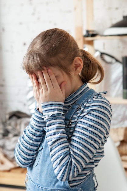 Fille blonde frustrée de 8 ans couvrant son visage avec