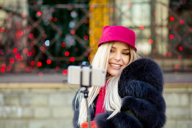 Fille blonde gaie faisant l'autoportrait avec un téléphone intelligent