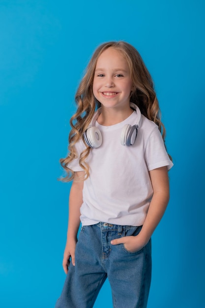 fille blonde en jeans et un T-shirt blanc écoute de la musique avec des écouteurs et des danses