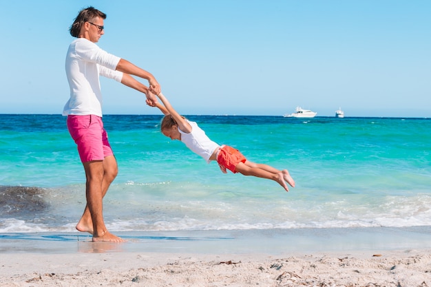 fille blonde jouant avec son père à la plage