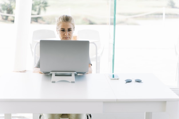 Fille blonde avec des lunettes travaillant avec un ordinateur portable