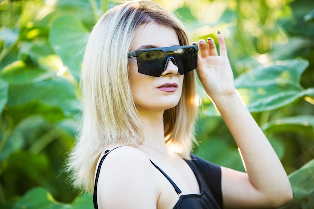 Fille blonde en maillot de bain noir posant avec des lunettes de soleil