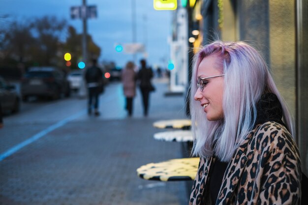 Fille blonde à la mode avec des lunettes en manteau léopard assis dans