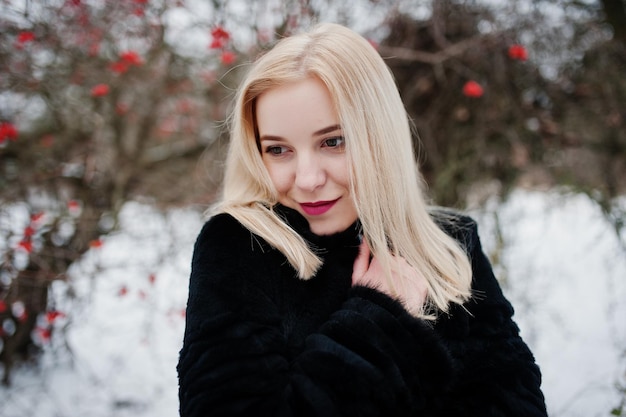 Fille blonde posée au jour de neige d'hiver.