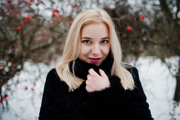 Fille blonde posée au jour de neige en hiver.