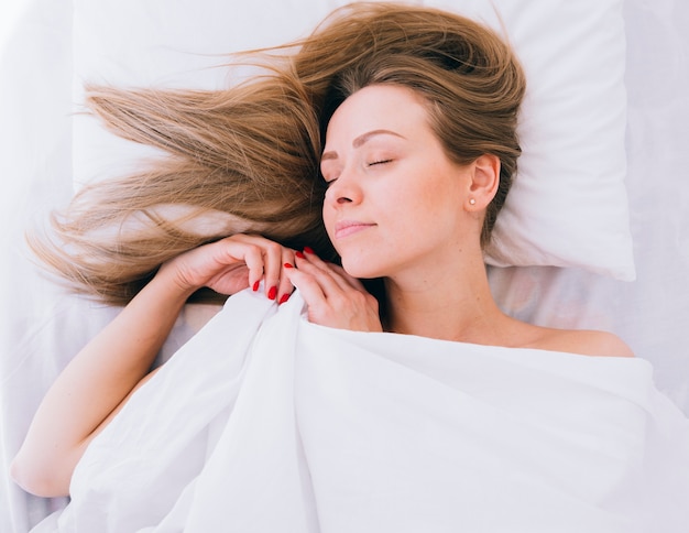 Fille blonde qui dort sur le lit