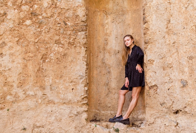 La fille blonde regarde à gauche en robe noire sur fond de pierre