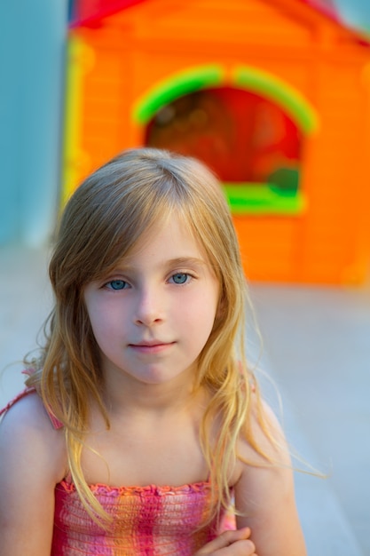 Fille blonde souriante dans une aire de jeux extérieure