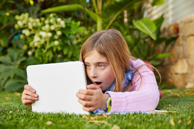 Fille blonde avec tablette, allongé sur le gazon