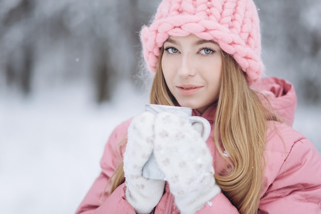 Fille blonde avec une tasse de thé chaud à l'extérieur dans le parc d'hiver