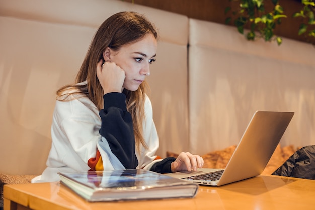 Photo fille blonde travaillant avec un ordinateur portable gris