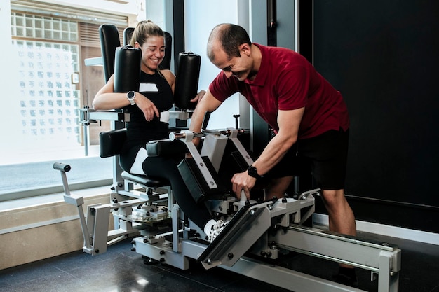 Fille blonde travaillant avec son entraîneur personnel sur une machine de gym