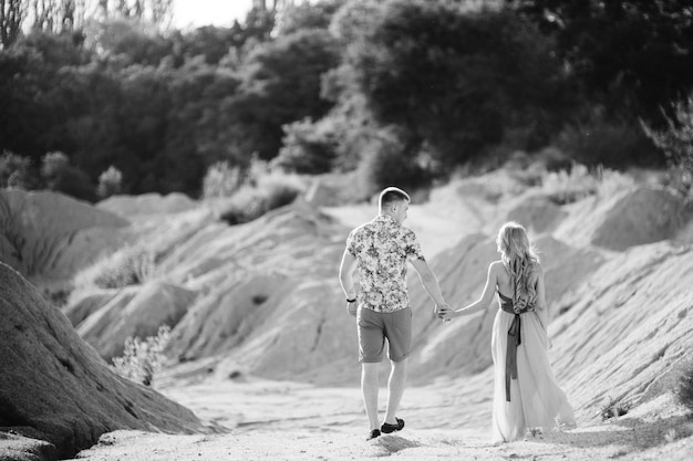 Fille blonde vêtue d'une robe bleu clair et un gars vêtu d'un short léger et d'une chemise courte dans une carrière de granit