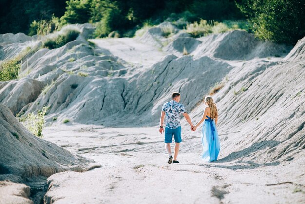 Fille blonde vêtue d'une robe bleu clair et un gars vêtu d'un short léger et d'une chemise courte dans une carrière de granit