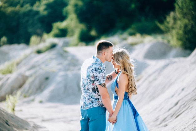 Fille blonde vêtue d'une robe bleu clair et un gars vêtu d'un short léger et d'une chemise courte dans une carrière de granit