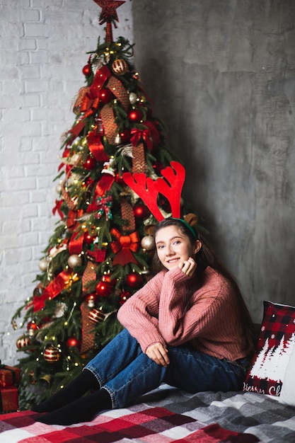 Fille avec des bois de cerf sur le fond de l'arbre de Noël.