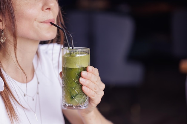 Une fille boit un cocktail frais et sain dans un café moderne