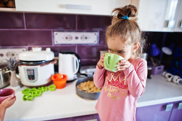 Une fille boit de la compote à la cuisine des moments heureux pour les enfants