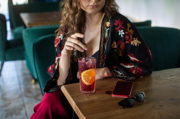 la fille boit un délicieux cocktail sucré et regarde dans le téléphone une journée de détente incroyable