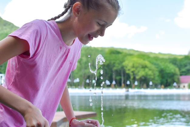 fille boit de l'eau de source de la fontaine Boire de l'eau minérale à l'air frais