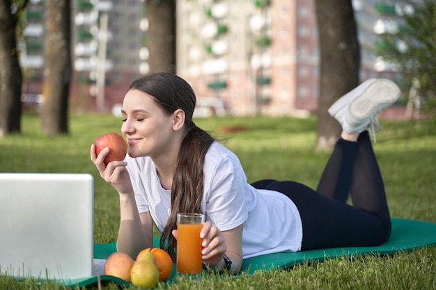 Fille en bonne santé athlétique tenant allongé sur la pelouse et tenant une pomme