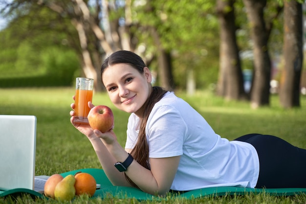 Fille en bonne santé athlétique tenant allongé sur la pelouse et tenant une pomme