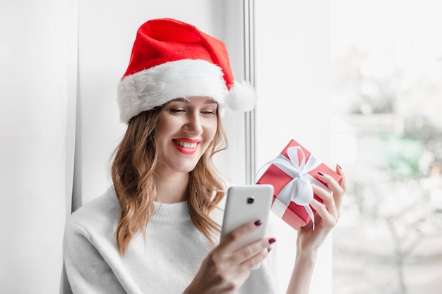 fille en bonnet de noel tenant une boîte-cadeau