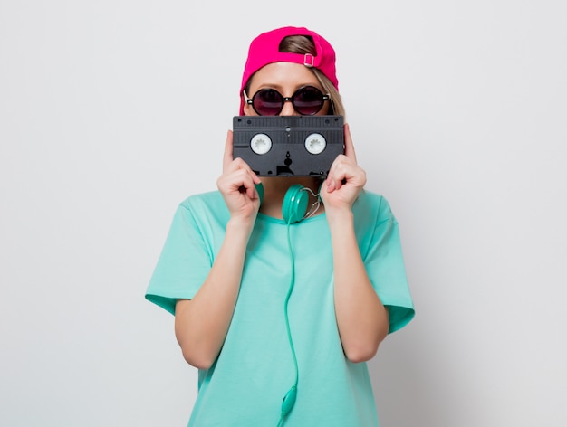 fille en bonnet rose et t-shirt bleu avec cassette VHS