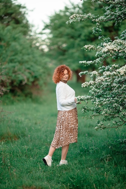 Fille bouclée aux cheveux rouges de la nature dans le jardin