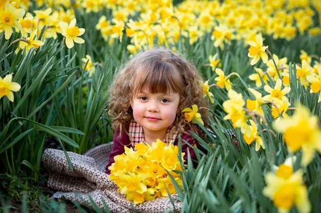 Photo une fille bouclée tenant un bouquet de narcises jaunes dans le jardin