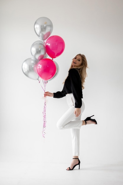 Une fille avec un bouquet de ballons roses et argentés