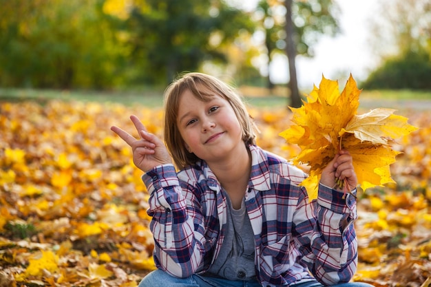 Fille avec un bouquet de feuilles d'automne jaunes