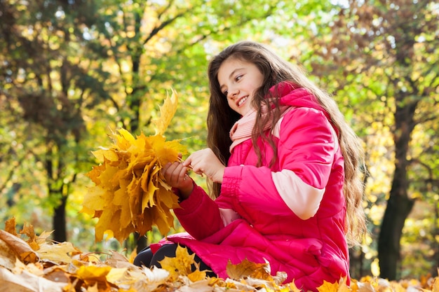 Fille avec bouquet de feuilles d'automne