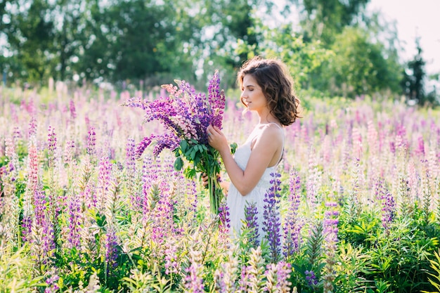 Fille avec un bouquet de lupin sur le terrain