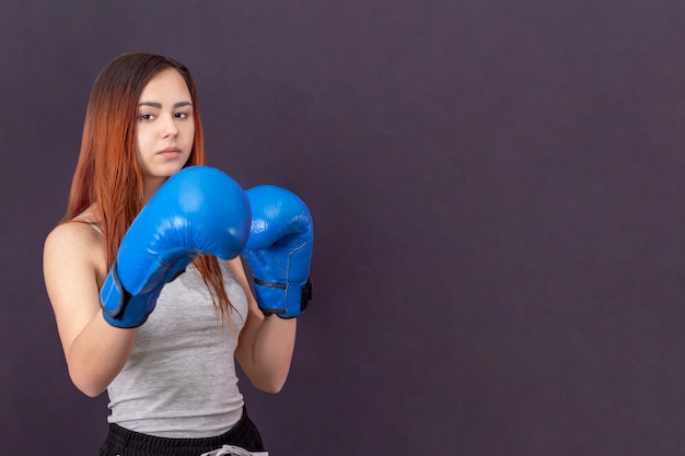 Fille de boxeur en sueur avec des gants de boxe debout