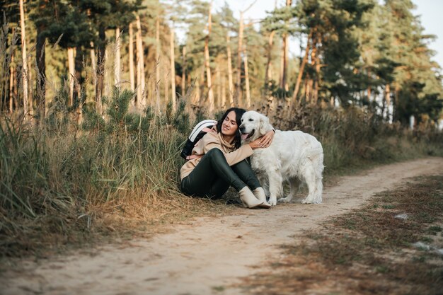 fille brune avec chien golden retriever blanc sur le chemin de la forêt