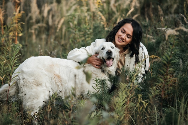 Fille brune avec chien golden retriever blanc sur le terrain