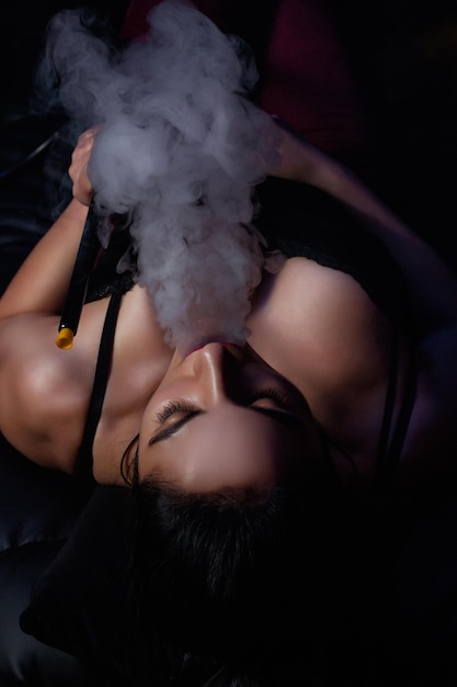 La fille brune fume un narguilé