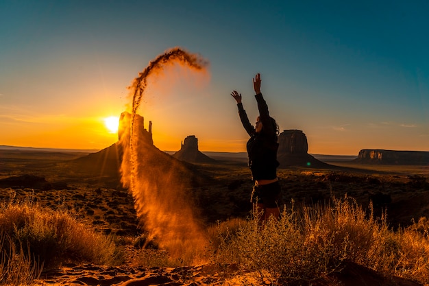 Une fille brune lifestyle à l'aube de Monument Valley jouant avec le sable rouge, Utah